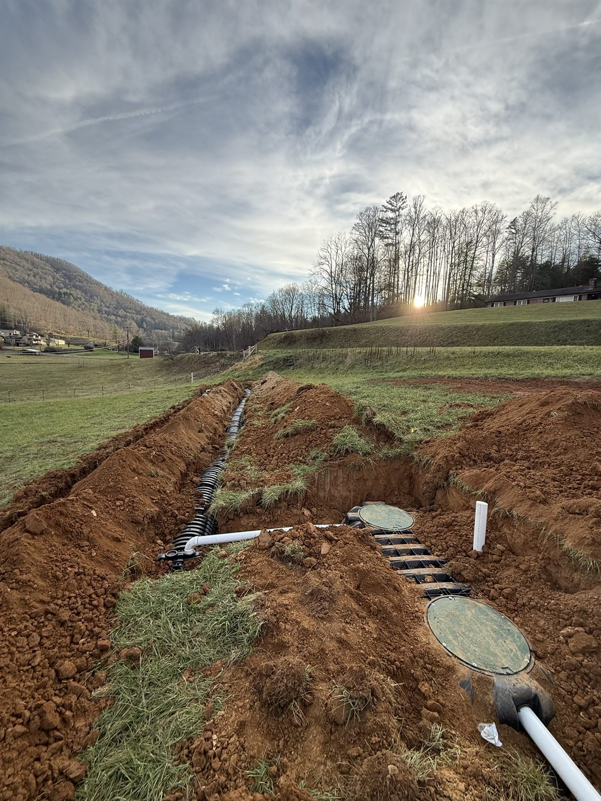 Drainage line trenched across a pasture at sunset in Western NC