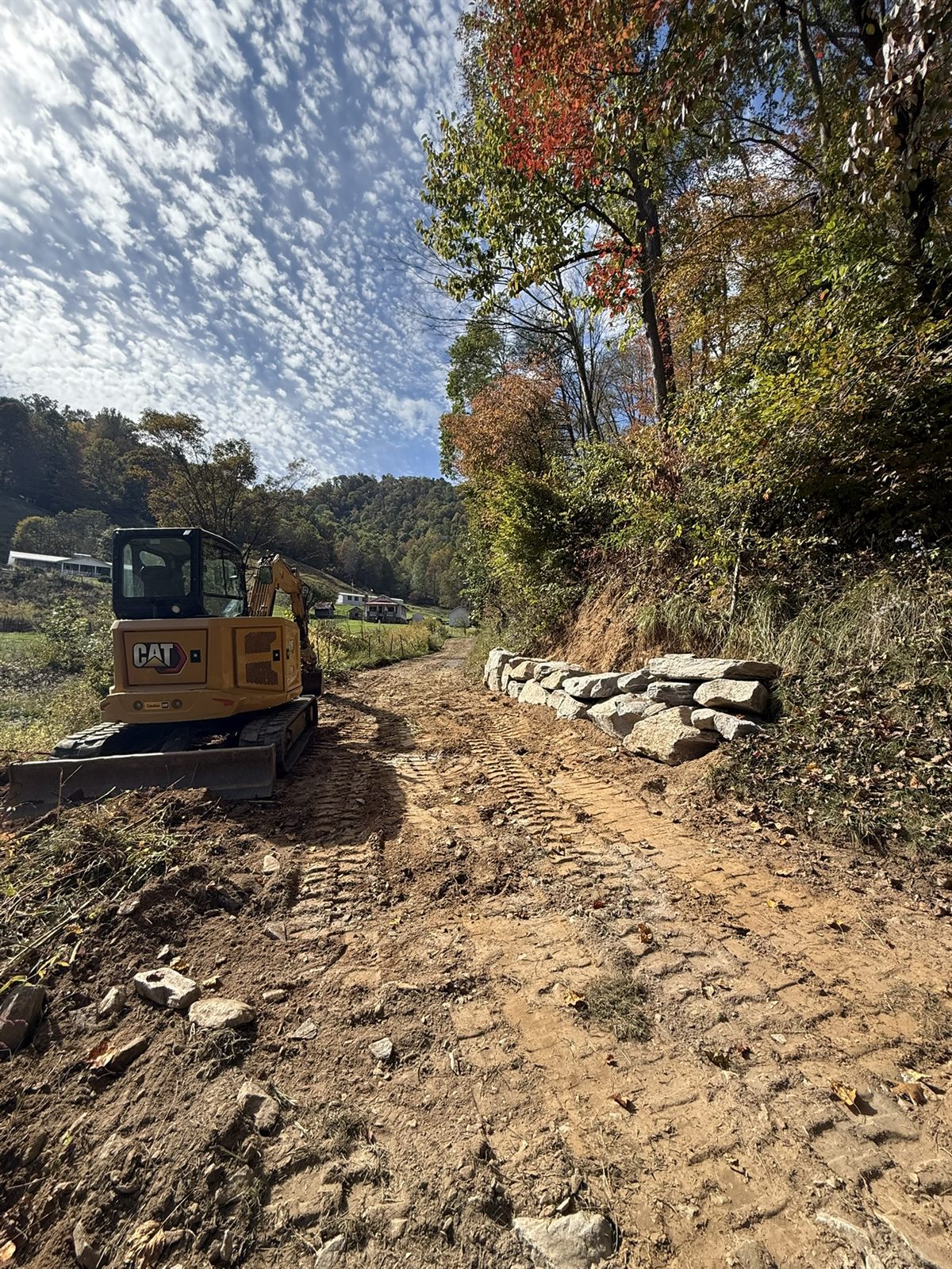 Excavator cutting a road grade into a hillside with fall color in Western NC