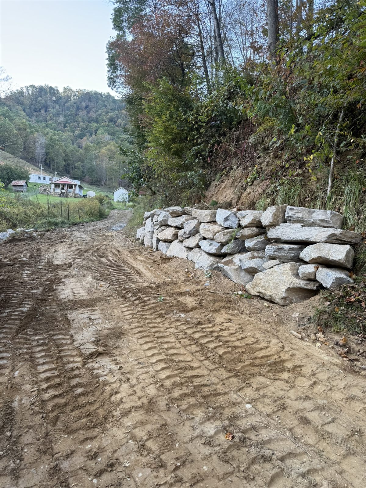 Finished boulder retaining wall along a mountain driveway in fall, Western NC