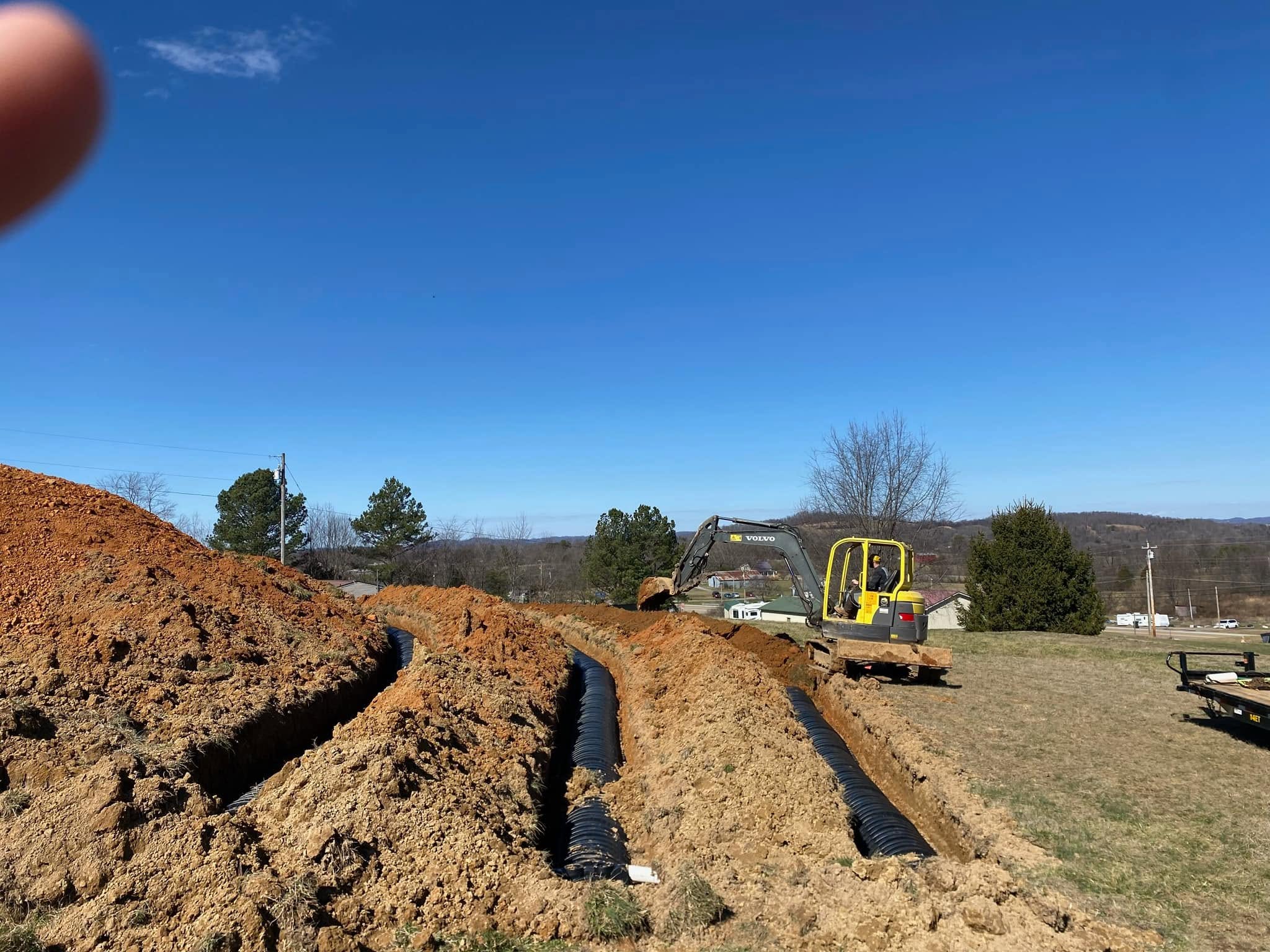 Drain-field laterals trenched on a site with excavator working