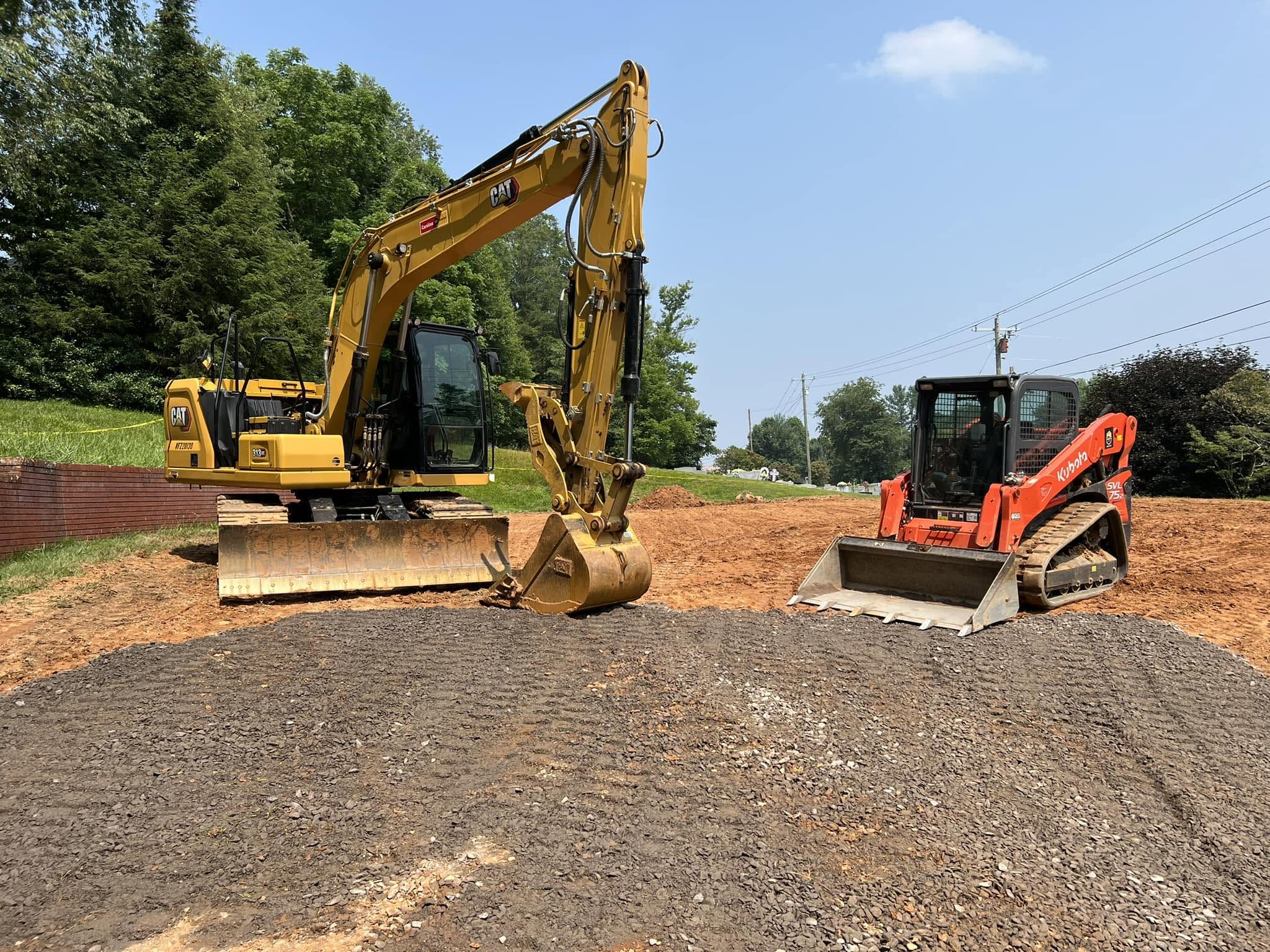 Excavator and skid steer staged on a graded site pad in Western NC